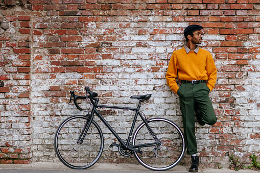 Young cool guy with a racing bike in the streets of city in front of a brick wall