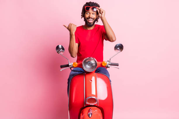 istock Portrait of handsome cheery guy riding moped showing copy space new solution isolated over pink pastel color background 1317620820