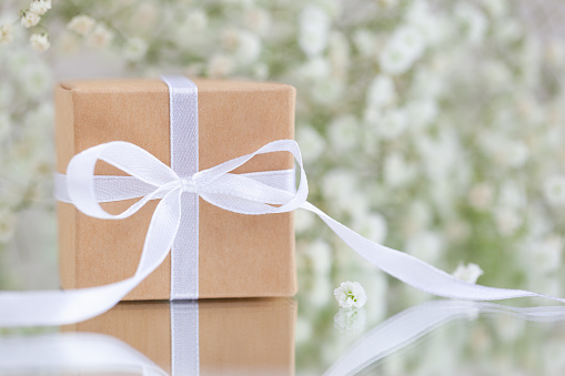 Gift box wrapped in brown paper with white gypsophila paniculataflowers. Greeting card.