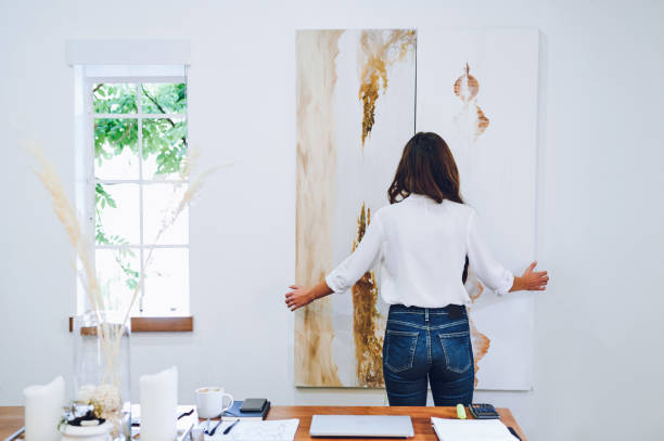 Shot Of An Unrecognizable Businesswoman Standing Alone In Her Home Office And Rearranging A Canvas Painting On Her Wall