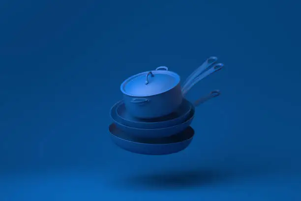 Photo of Blue Flying pan and Kitchen pot floating in blue background. minimal concept idea creative. monochrome. 3D render.