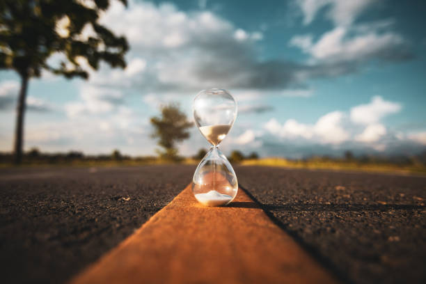 open road and hourglass about time of journey life concept with copy space. time stock pictures, royalty-free photos & images