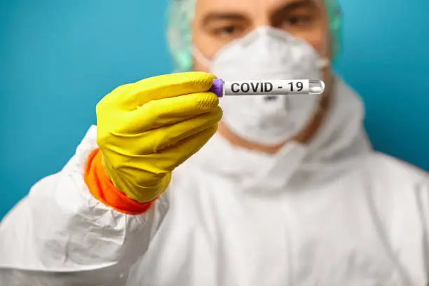 Image of doctor wearing respirator mask and protective coverall holding a express test result for the Coronavirus. Covid-19 sample. Corona virus outbreaking. Epidemic virus Respiratory Syndrome. China, Wuhan.