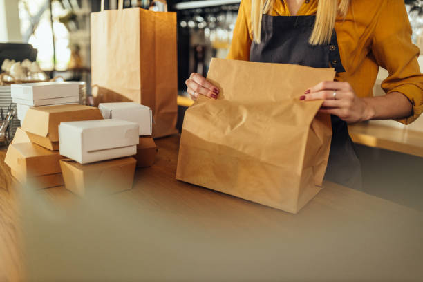 frau verpackt lebensmittel in papiertüten - lunch take out food bag paper bag stock-fotos und bilder