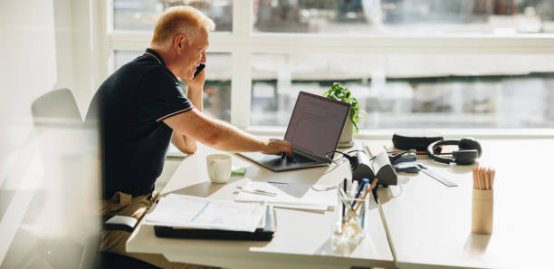 istock Businessman talking over phone while working on laptop 1317634763