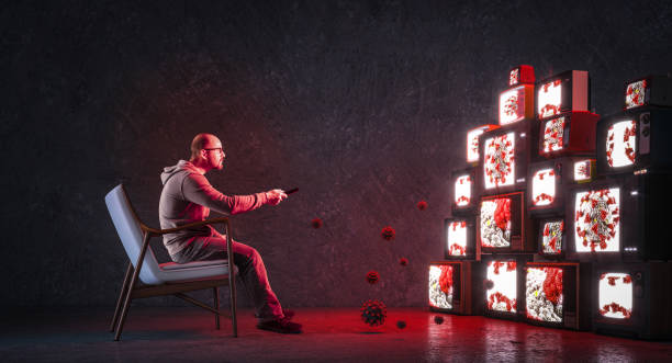 man on an armchair watching many televisions