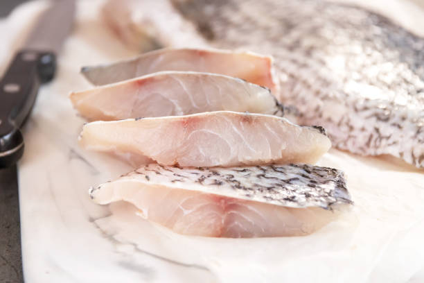 Fresh sea bass fish fillets on marble cutting board; selective focus and copy space. Fresh sea bass fish fillets on marble cutting board; selective focus and copy space. bass fish photos stock pictures, royalty-free photos & images
