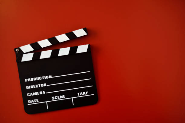 istock Black movie clapper on red background 1317637780