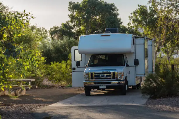 C-type camper with slideouts standing on the campground on concrete