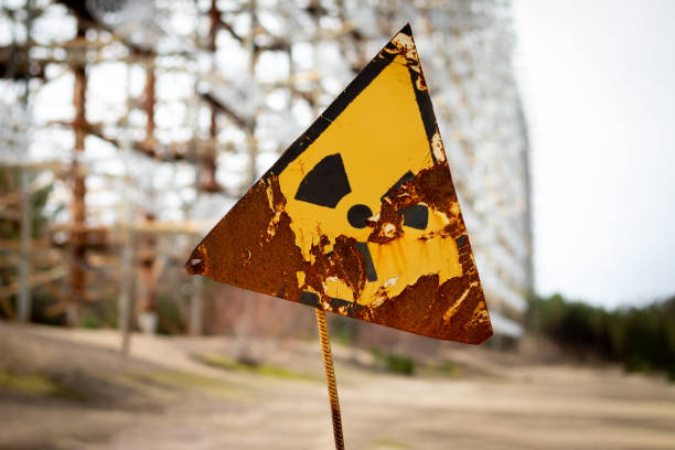 old yellow radiation sign against the duga radar antenna complex. chernobyl exclusion zone, ukraine. tilt-shift effect - environmental damage audio imagens e fotografias de stock