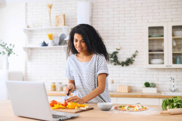 istock Nice smiling biracial girl cooking while watching master-class on a laptop 1317639314