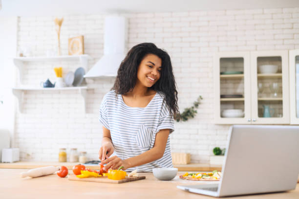 istock Nice smiling biracial girl cooking while watching master-class on a laptop 1317639412