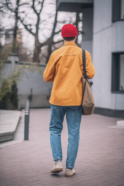 istock Man in an orange jacket walking down the street 1317639976