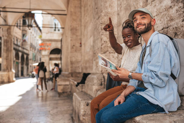 felice coppia di turisti alla scoperta della città leggendo la guida e la mappa della città - guidebook foto e immagini stock