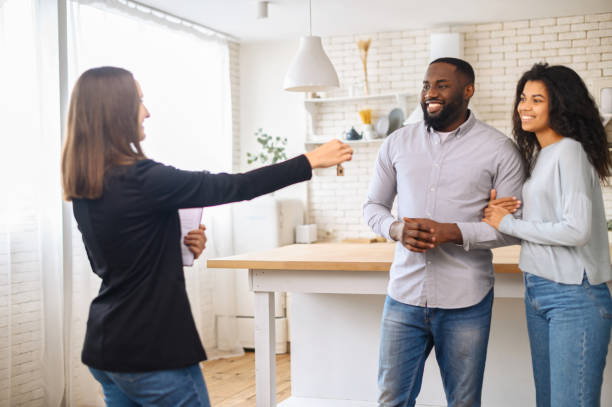 Cute African-American couple in love moving in new house Relocation concept. A smiling cheerful multiracial couple receives the keys to a new home from a real estate agent, smiling African man and woman rent new apartment estate agent stock pictures, royalty-free photos & images