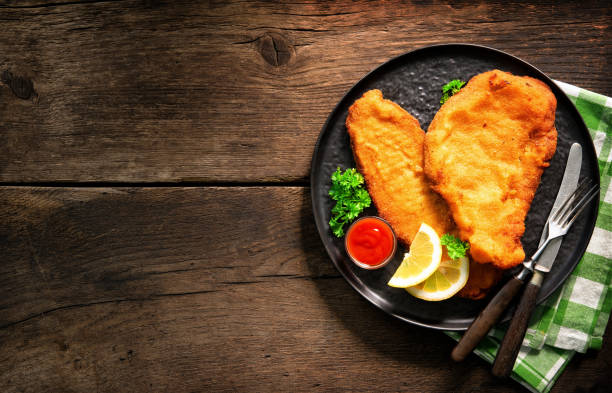 Homemade breaded wiener schnitzel served with parsley and lemon slices Homemade breaded wiener schnitzel served with parsley and lemon slices on dark wooden table schnitzel stock pictures, royalty-free photos & images