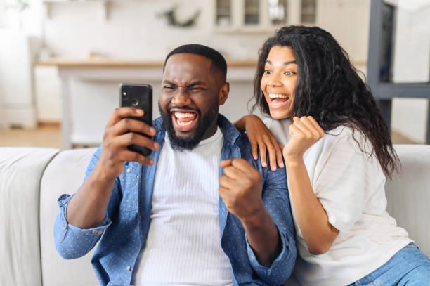 istock Excited overjoyed couple resting on couch holding smart phone 1317641798