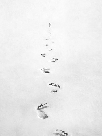 illustration of black and white footsteps in the sand, following person concept