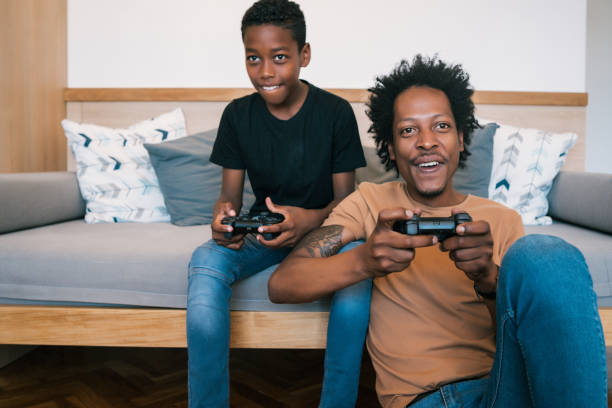 istock Father and son playing video games together at home. 1317642635