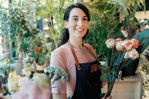 Portrait of beautiful caucasian girl self-employed in flower shop, smiling and looking at camera.