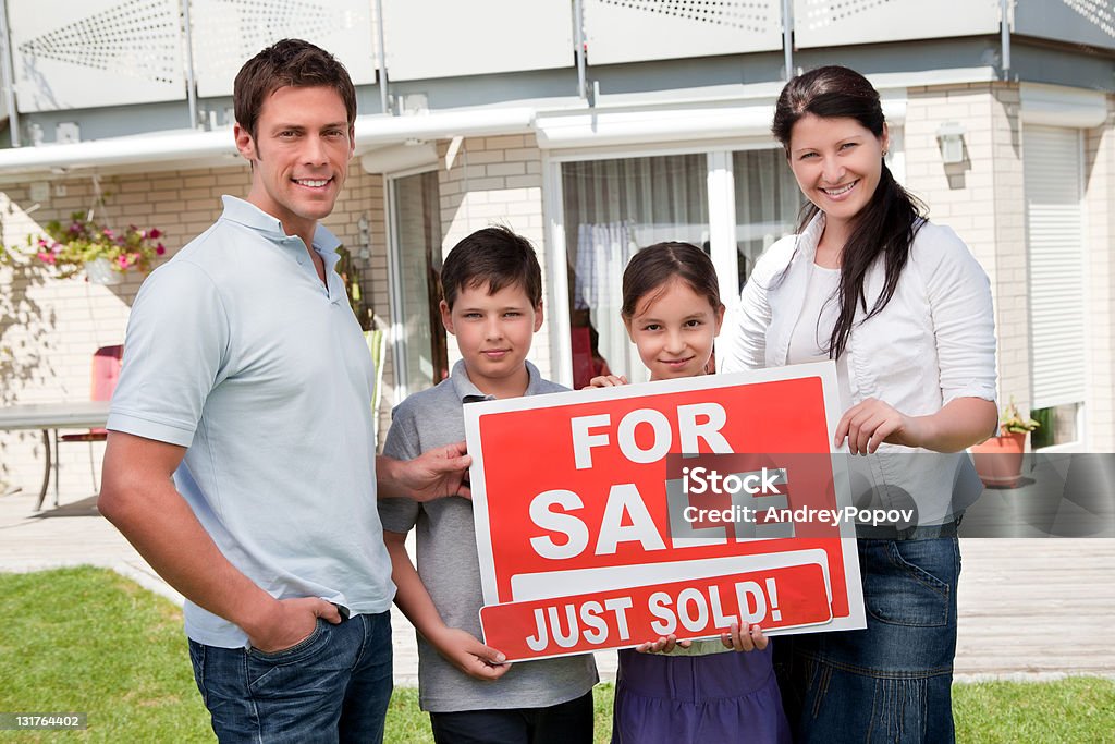 Familia con una señal de venta fuera de su nuevo hogar - Foto de stock de Adulto libre de derechos