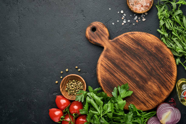 Fresh tarragon. Branch of fresh herb seasoning and cooking products, tomatoes, peppers, onions and olive oil on black concrete background. Cooking Background. Top view. Fresh tarragon. Branch of fresh herb seasoning and cooking products, tomatoes, peppers, onions and olive oil on black concrete background. Cooking Background. Top view. tarragon cutting board vegetable herb stock pictures, royalty-free photos & images