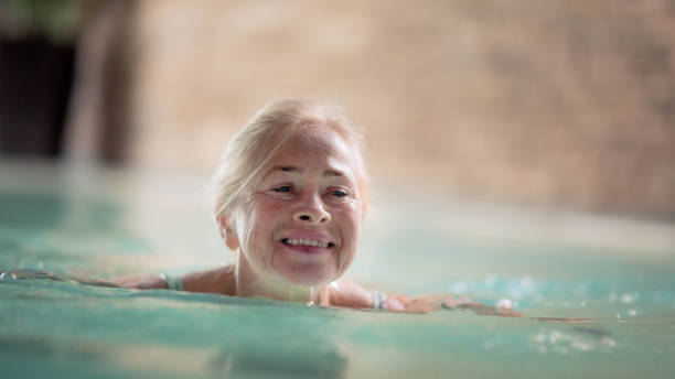 verticale de femme aînée dans la piscine intérieure, natation. - health spa swimming pool relaxation indoors photos et images de collection