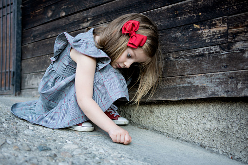 Adorable little girl wear beautiful dress writing on concrete