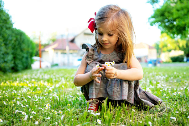 Adobarle little girl in beautiful dress picking daisy