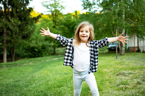 Happy Little girl running with open arms in the park nature