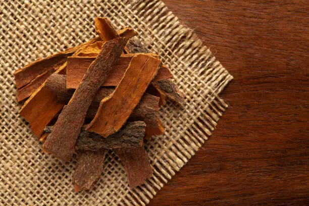 Photo of close-up of Organic cinnamon ( Cinnamomum Verum) or dalchini on the wooden top background and jute mat. Pile of Indian Aromatic Spice.