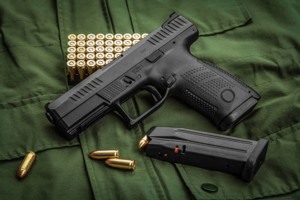 modern semi-automatic pistol and cartridges for it on a green background. a short-barreled weapon for self-defense. arming the army and police. - handgun imagens e fotografias de stock