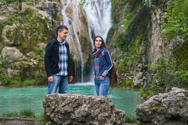 Man and a woman walking in nature together near a waterfall
