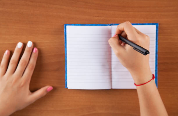 istock Woman writes in her notebook. Wooden table. 1317663470