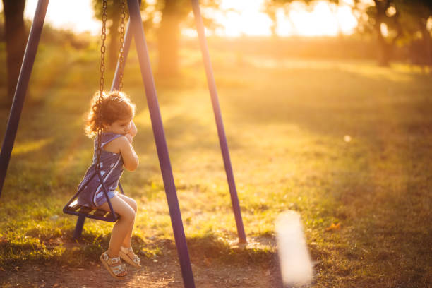 istock Little sad girl swinging at sunset 1317667939