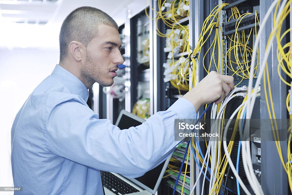 Hombre de negocios con ordenador portátil en la sala de servidores de red - Foto de stock de Hombres libre de derechos