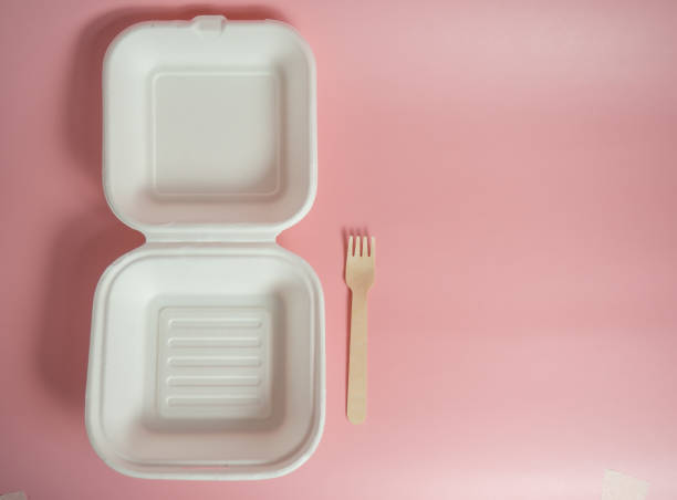 istock white paper food container and wooden fork on pink background, copy space 1317672357