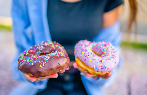 istock Woman holding and showing colorful doughnuts 1317672476