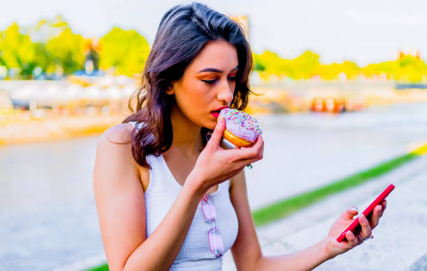 istock Woman using smartphone and eating donut 1317673208