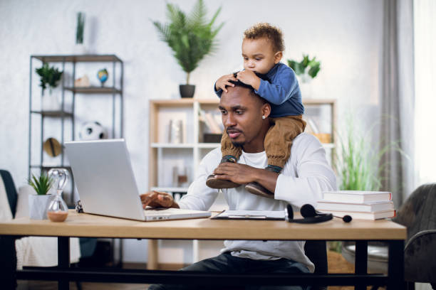 istock Afro american man with son on neck working on laptop 1317675625
