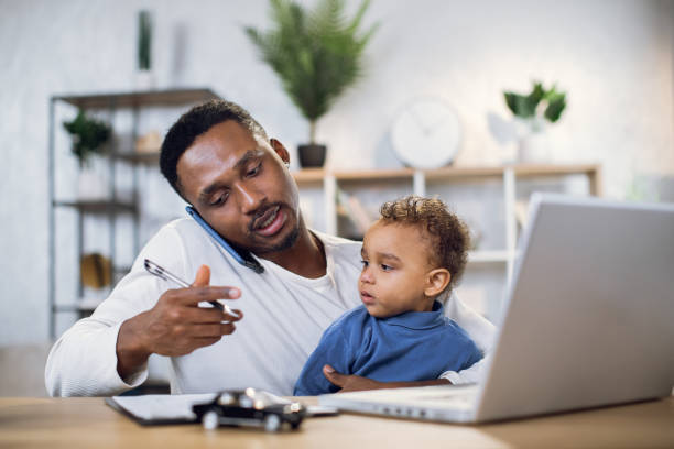istock Man with son on knees working on laptop at home 1317675791