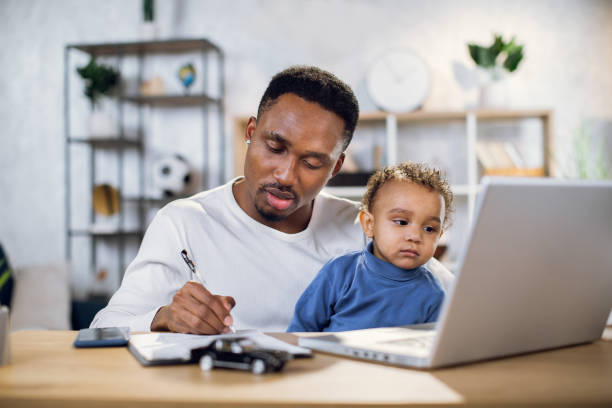 istock Man with son on knees working on laptop at home 1317675798