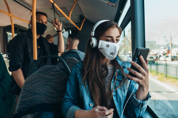istock Young woman using a smartphone and wearing protective maskin the bus 1317677097