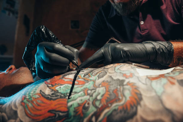 istock Tattoo artist hands wearing black gloves while holding a machine 1317677163