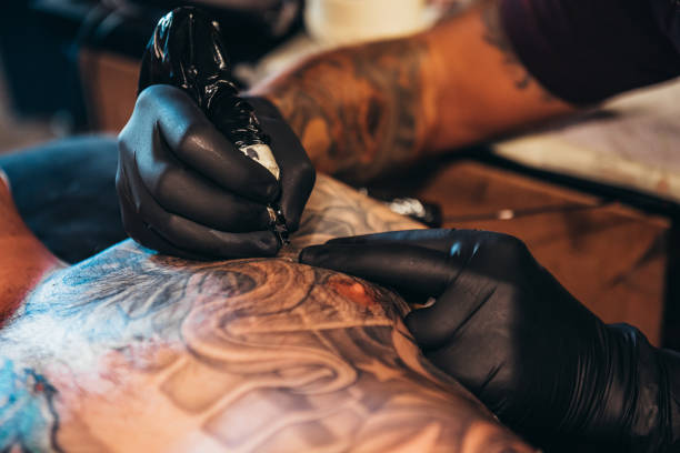 istock Tattoo artist hands wearing black gloves while holding a machine 1317677164