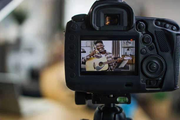 istock Cheerful man recording video on camera while playing guitar 1317677433
