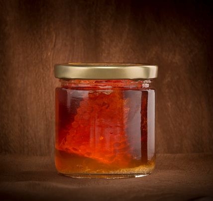 close-up of honey container with piece of honeycomb inside. studio photo.