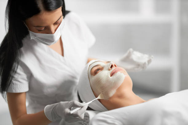 Beautician applying special white cream for patient. stock photo