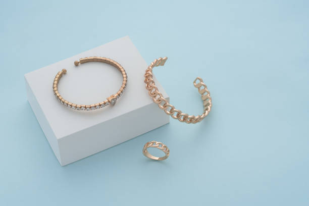istock Golden bracelets and ring on white box on blue background with copy space 1317681965