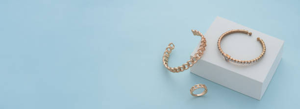 istock Panoramic shot of golden bracelets and ring on white box on blue background 1317681993